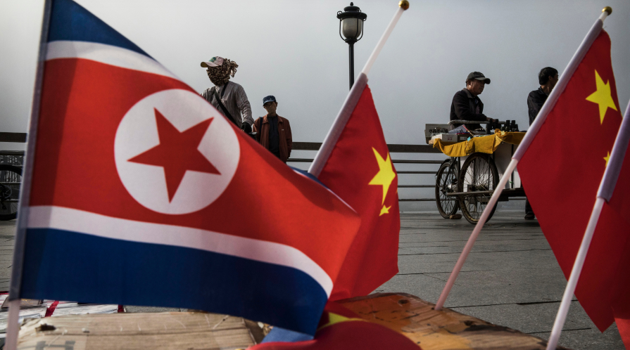 North Korean and Chinese flags are displayed side-by-side on a pier.