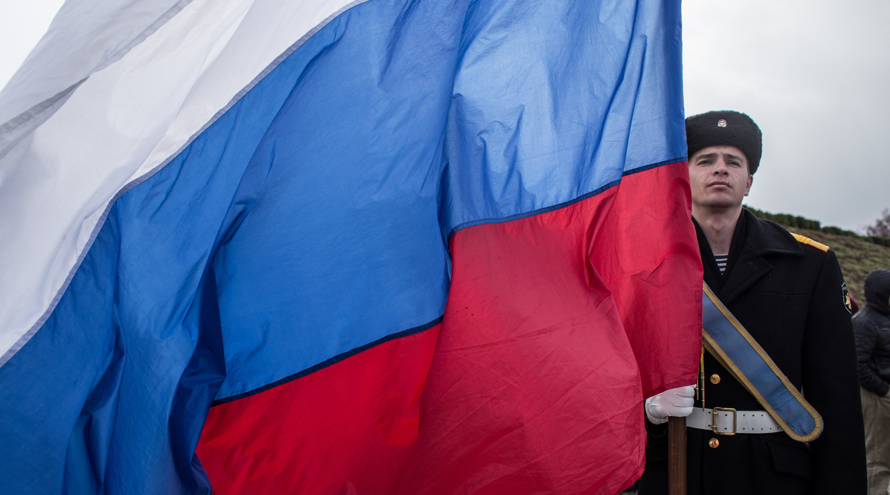 A Russian soldier stands with a large Russian flag